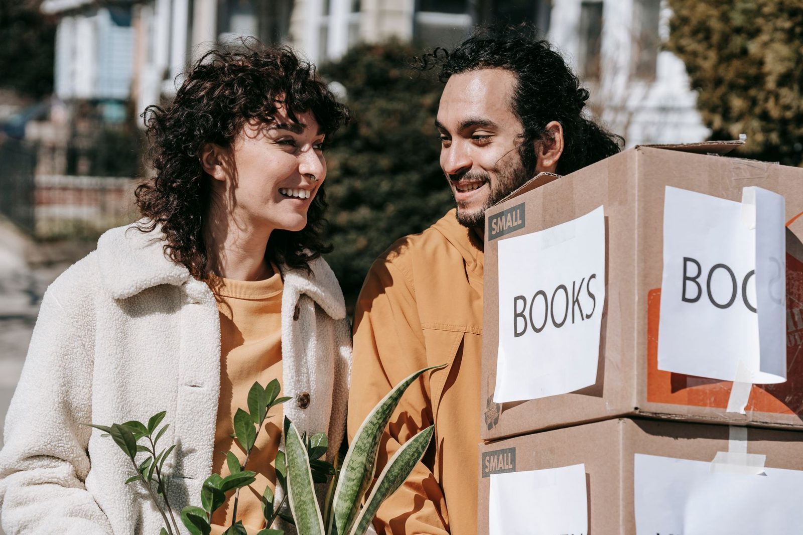 Smiling couple carrying moving boxes into their new home